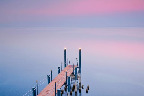 Rosa Abendstimmung ueber dem Bodensee mit beleuchtetem Badesteg zum See