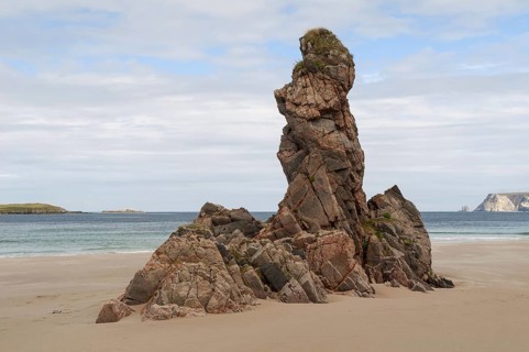 Outcrop of pink Lewisian gneiss rocks protruding from beach
