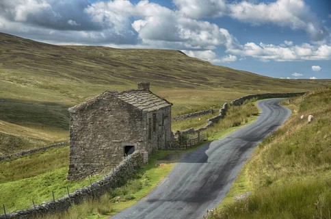 View of dry stone walls and stone barn beside the road