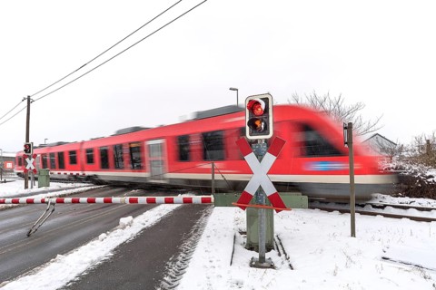 Passing train at a level crossing with barriers in sleet
