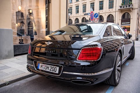 Parked luxury sedan Bentley Flying Spur First Edition in front of fashion shop Boutique Dior