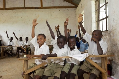 Children with their hands up in the classroom of a rural school
