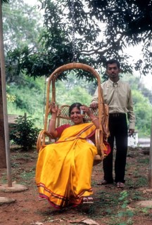 Mother sitting in hanging cane chair and her son standing nearby at Singara