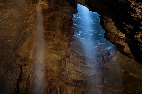 View of upland stream waterfall flowing down chasm into chamber of cave
