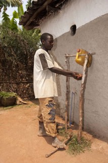 Man washes hands under self-made water tap from plastic container