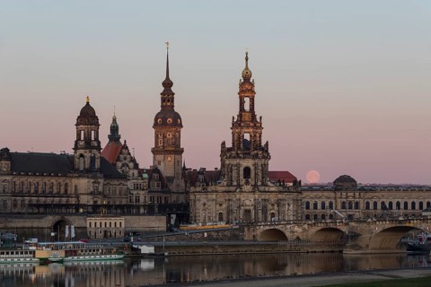 Sunrise and full moon behind the silhouette of the old town with the towers of the Staendehaus