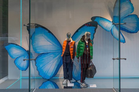 Shop window with fashionable mannequins and large paper butterflies