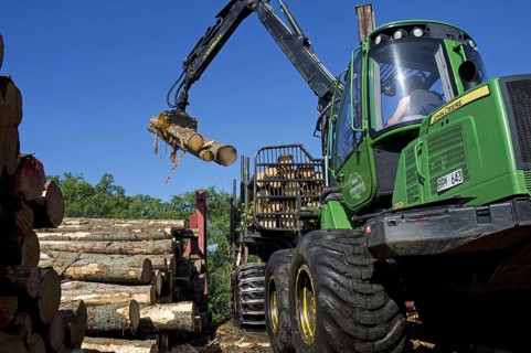 John Deere 1010E Forwarder loading logs onto timber barge