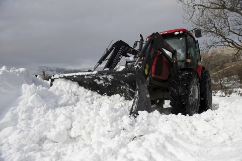 Zetor tractor with loader clears snow from blocked country road after snowstorm
