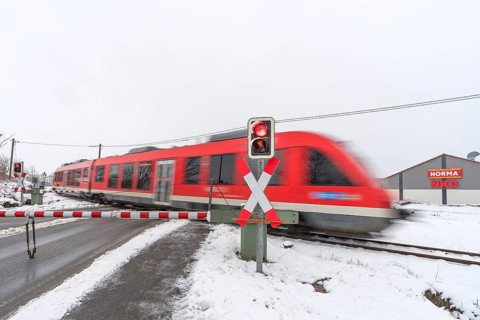 Passing train at a level crossing with barriers in sleet