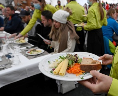 Service staff with starter plate of mixed salad with sliced cheese and sprouts