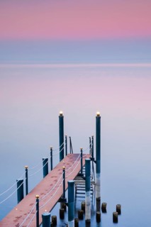 Rosa Abendstimmung ueber dem Bodensee mit beleuchtetem Badesteg zum See