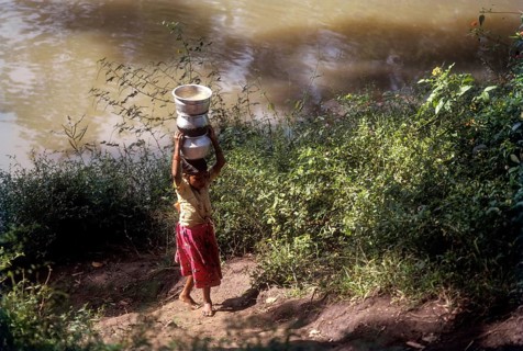 Betta Kurumba tribal girl carrying water in Moyar river at Mudumalai