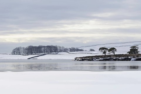 View of a partially frozen and snow-covered glacial lake