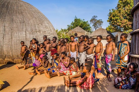 Children watch with interest at traditional customs in real African village