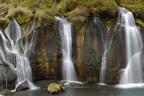 Cascades and waterfalls flowing from the lava field into the river