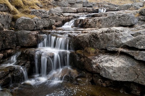 High mountain stream pouring over limestone pavement in front of flowing into a precipice