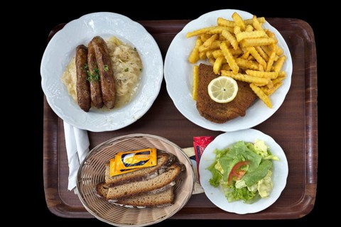 Bratwurst with sauerkraut and bread and cordon bleu with french fries on a tray on a black background