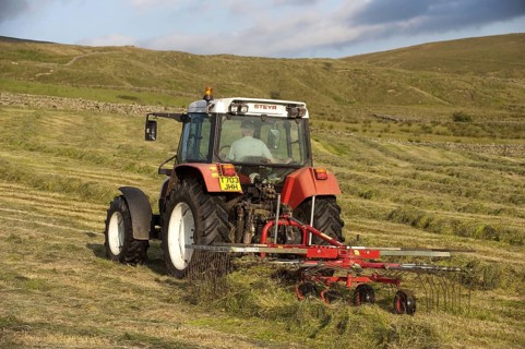 Styer 9078 Tractor rowing up grass on a hill farm to make big bale silage