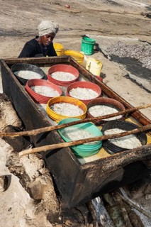 Frau kocht Sardellen fuer Fischsauce ueber Feuerstelle