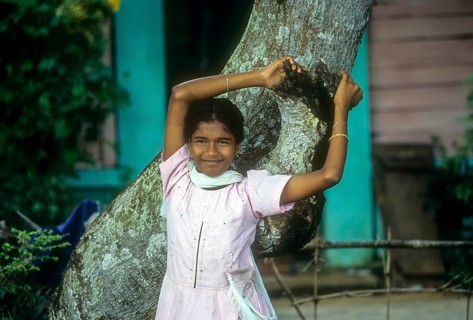 A girl leaning on a tree near backwater of Kuttanad