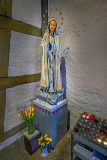Figure of Mary with floral decoration and offering candles