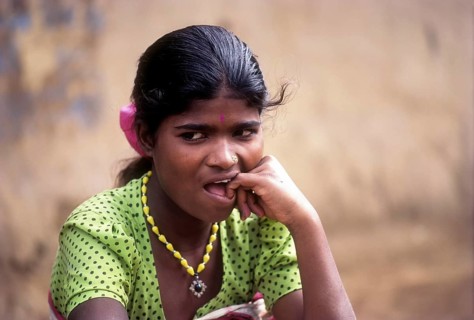 Betta Kurumba belle sitting in front of her hut