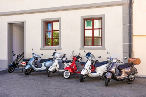 Alte und moderne Vespa Roller vor Hauswand