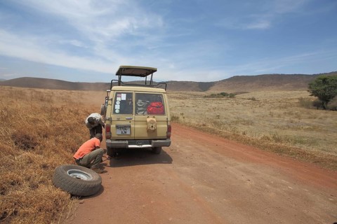 Jeep with spare wheel changing tyre due to car breakdown in Ngorongoro Crater