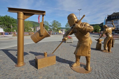 Golden sculptures with workers for steel production and steel processing with tools in the foundry in Alf