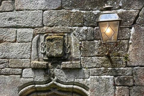 Coat of arms and streetlamp on the facade of an old stone house