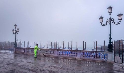 City cleaning staff in the morning fog at the gondola harbour in front of St. Mark's Square