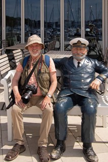 Elderly gentleman sitting next to captain figure