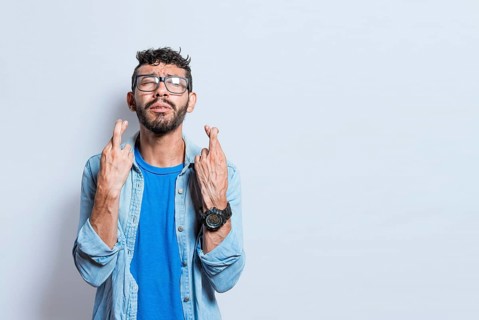 Worried person crossing his fingers making a wish