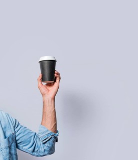 Close up of hand holding a paper cup of coffee. Hand holding a coffee to go on isolated background