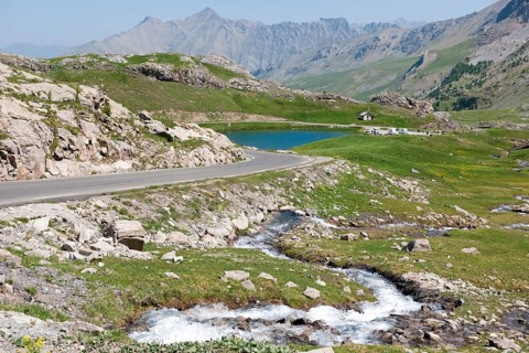 View of alpine plateau with Lac des Eissaupres next to mountain road from Route de Col de la Bonette e Restefond