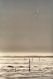Wind turbines rising from cloud cover