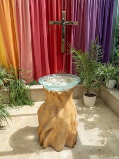 Glass baptismal fountain on a base of ash wood and crucifix in the entrance area of Germany's first private ecumenical motorway church Geiselwind 'Light on our way' on the A 3 between Wuerzburg and Nu...
