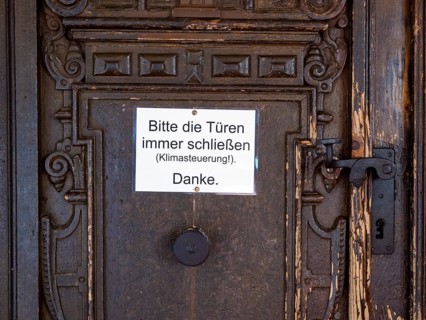 Portal of the Catholic parish church of St. George with sign 'Please always close the bags