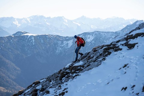 Mountaineers on the rocky summit ridge with the first snow in autumn