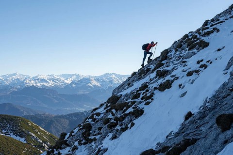 Mountaineers on the rocky summit ridge with the first snow in autumn