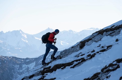 Mountaineers on the rocky summit ridge with the first snow in autumn