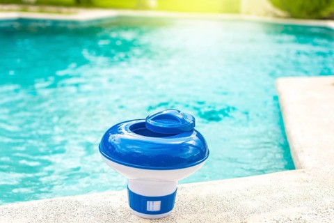 A chlorine dispenser for swimming pools with blue water in the background. Dosing float for swimming pool chlorination