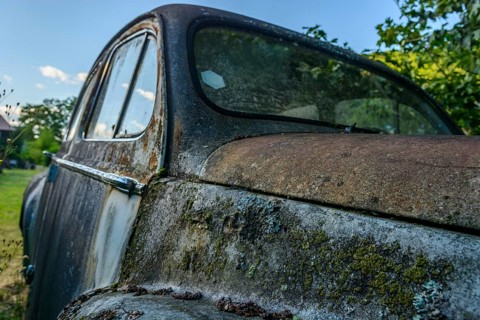 Old car rolled for scrapping in a meadow. Alsace