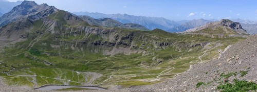 View from Cime de la Bonette on high alpine mountain landscape with road to Col de la Bonette in the background on the right
