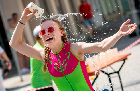 A runner refreshes herself with a cup of water at the 27th city triathlon in Erding