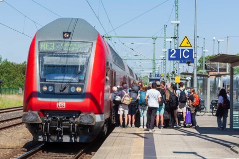 Many people standing crowded on a platform in front of a local train