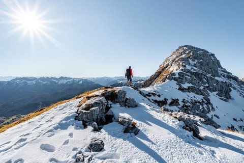 Climbers on the rocky summit ridge with first snow in autumn