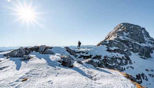 Climbers on the rocky summit ridge with first snow in autumn
