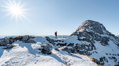 Climbers on the rocky summit ridge with first snow in autumn